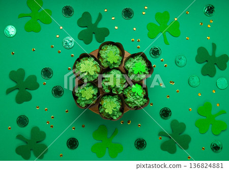St. Patrick's Day vanilla cupcakes with green frosting and clover decorations on green background. Irish holiday dessert concept. Top view, copy space St. Patrick's Day vanilla cupcakes with green frosting and clover decorations on green background. Irish holiday dessert concept. Top view, copy space 136824881
