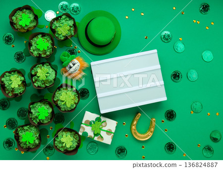 St. Patrick's Day vanilla cupcakes with green frosting and clover decorations on green background. Irish holiday dessert concept. Top view, copy space 136824887