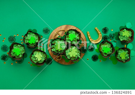 St. Patrick's Day vanilla cupcakes with green frosting and clover decorations on green background. Irish holiday dessert concept. Top view, copy space St. Patrick's Day vanilla cupcakes with green frosting and clover decorations on green background. Irish holiday dessert concept. Top view, copy space 136824891