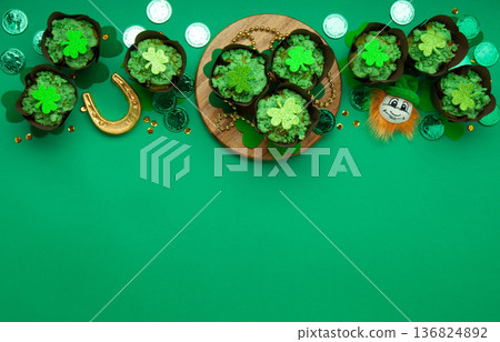 St. Patrick's Day vanilla cupcakes with green frosting and shiny clover decorations on green background. Irish holiday dessert concept. Top view, copy space St. Patrick's Day vanilla cupcakes with green frosting and shiny clover decorations on green background. Irish holiday dessert concept. Top view, copy space 136824892