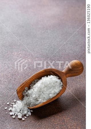 sea salt crystals in wooden scoop on brown background sea salt crystals in wooden scoop on brown background 136825190