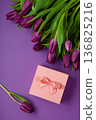 Holiday gift with pink ribbon bow, bouquet of purple tulips flower on purple background.  Happy Mother's Day spring design. 136825216