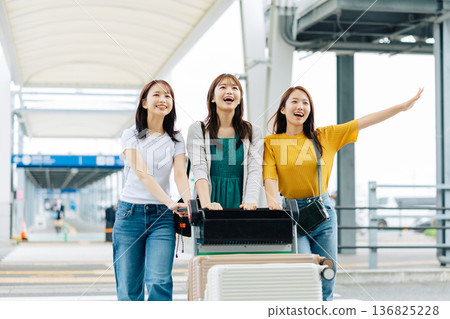 Three women using a cart to carry suitcases at the airport. (Photography courtesy of Kansai International Airport (KIX)) 136825228