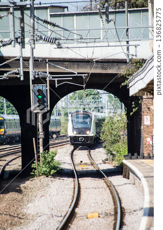 陽光明媚的月台上，列車正穿過倫敦郊區索索爾車站的高架隧道。 136825775