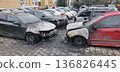 Front view of four fire-damaged cars with melted hoods and shattered windows 136826445