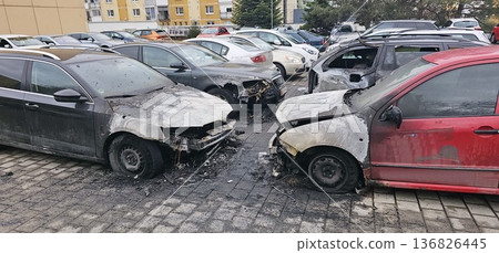 Front view of four fire-damaged cars with melted hoods and shattered windows Front view of four fire-damaged cars with melted hoods and shattered windows 136826445