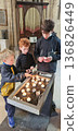 Three boys look at burning candles placed in a candle holder 136826449