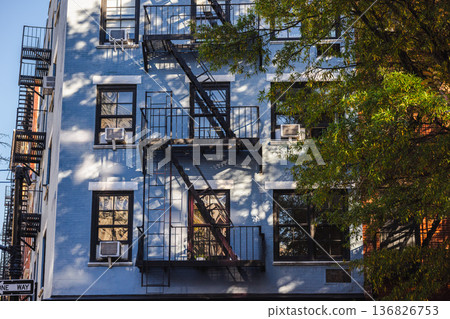 New York residential building facade with fire escape and tree shadows 136826753