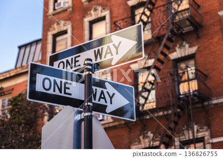 One way street signs on city corner with historic brick building and fire escape One way street signs on city corner with historic brick building and fire escape 136826755