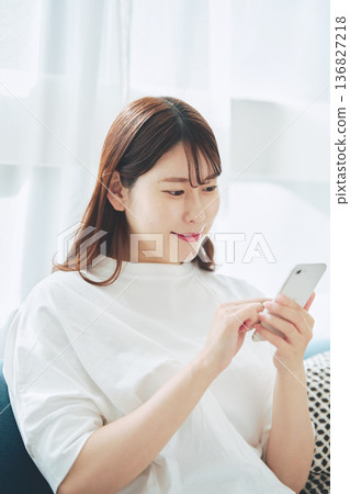 一位30多歲的女性在家中客廳使用智慧型手機的生活方式 136827218