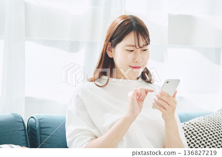 一位30多歲的女性在家中客廳使用智慧型手機的生活方式 136827219