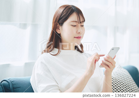 一位30多歲的女性在家中客廳使用智慧型手機的生活方式 136827224