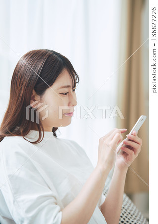 一位30多歲的女性在家中客廳使用智慧型手機的生活方式 136827226