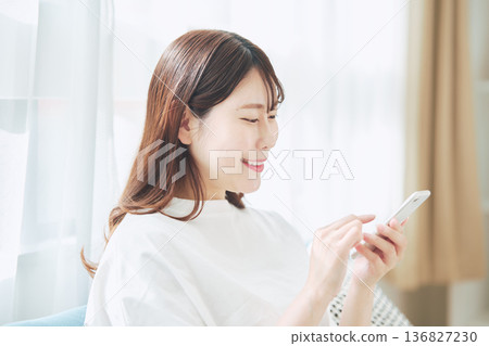 一位30多歲的女性在家中客廳使用智慧型手機的生活方式 136827230