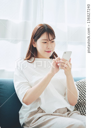 一位30多歲的女性在家中客廳使用智慧型手機的生活方式 136827240