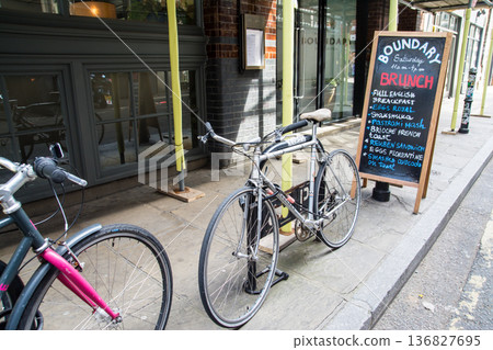 A bicycle parked on a sidewalk pipe and an English restaurant sign in Shoreditch, East London A bicycle parked on a sidewalk pipe and an English restaurant sign in Shoreditch, East London 136827695