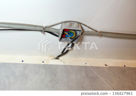The electrical wires in the protective corrugated cable tube and the junction box are neatly laid on the ceiling 136827961