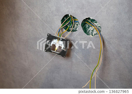 An electrical conduit box is built into the wall with wires sticking out as part of a home renovation  136827965