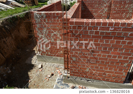 Brick walls rise up at a construction site. House under construction Brick walls rise up at a construction site. House under construction 136828016