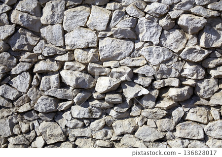 Natural stone wall showcases varied textures and colors in an outdoor setting during daylight hours Natural stone wall showcases varied textures and colors in an outdoor setting during daylight hours 136828017