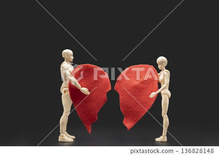 Conceptual image of two plastic mannequins holding two halves of a broken red heart on a black background, representing heartbreak, separation, and divorce. Conceptual image of two plastic mannequins holding two halves of a broken red heart on a black background, representing heartbreak, separation, and divorce. 136828148