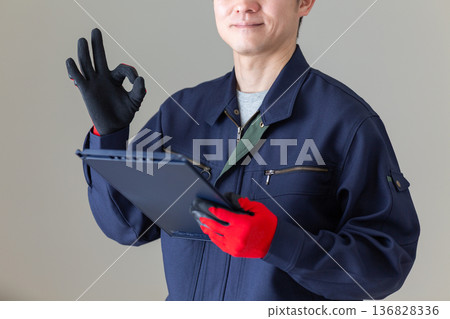 身著工作服的中年男性商務人士，手持活頁夾，比劃著一個圓圈。 136828336