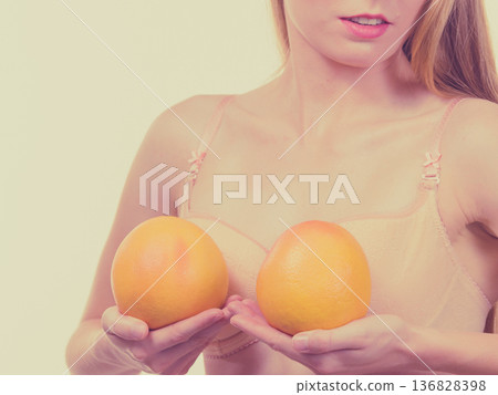 Woman small boobs holds big orange fruits Woman small boobs holds big orange fruits 136828398