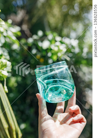 Holding a turquoise glass cup shining in natural light Holding a turquoise glass cup shining in natural light 136828556