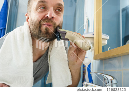 Man shaving trimming his beard Man shaving trimming his beard 136828823