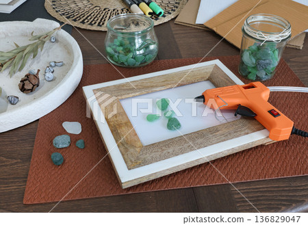 Sea glass in frame. Making art from natural materials. Glue gun and driftwood for picture. Hobbies and creativity. Reuse and nature, ecology.  136829047