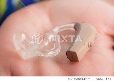 senior person holding hearing aid closeup 136829134