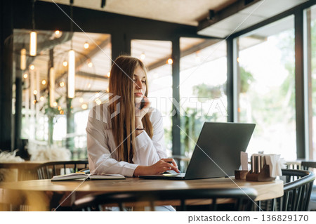 Student is with laptop. Young woman is in the cafe at daytime Student is with laptop. Young woman is in the cafe at daytime 136829170