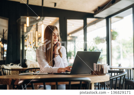 Student is with laptop. Young woman is in the cafe at daytime Student is with laptop. Young woman is in the cafe at daytime 136829171