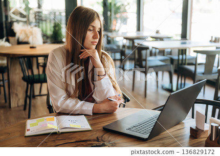 Student is with laptop. Young woman is in the cafe at daytime Student is with laptop. Young woman is in the cafe at daytime 136829172