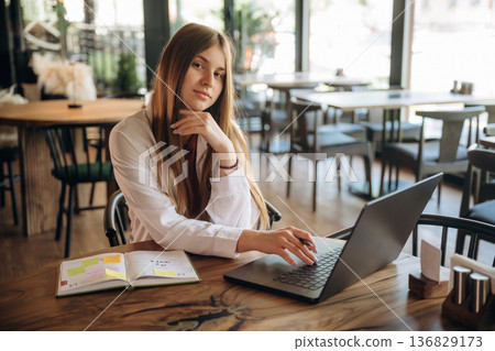 Student is with laptop. Young woman is in the cafe at daytime Student is with laptop. Young woman is in the cafe at daytime 136829173