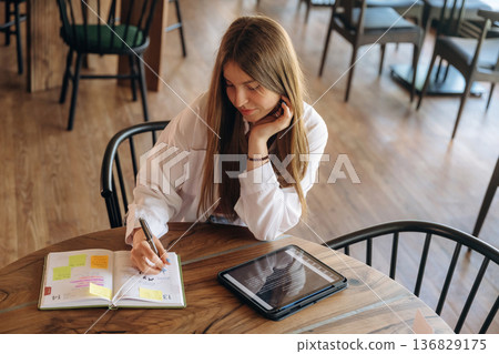 Digital tablet is on table. Young woman is in the cafe at daytime 136829175