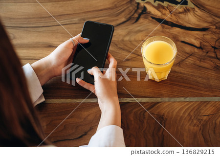 Orange juice. Close up view of teenage girl that is sitting in the cafe restaurant 136829215