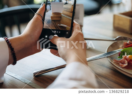 Scanning the QR code by smartphone. Close up view of teenage girl that is sitting in the cafe restaurant Scanning the QR code by smartphone. Close up view of teenage girl that is sitting in the cafe restaurant 136829218