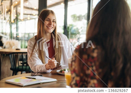 Smiling, talking, having fun. Two young women are together in the cafe restaurant Smiling, talking, having fun. Two young women are together in the cafe restaurant 136829267