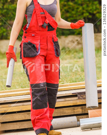 Woman carrying pipes on construction site 136829329