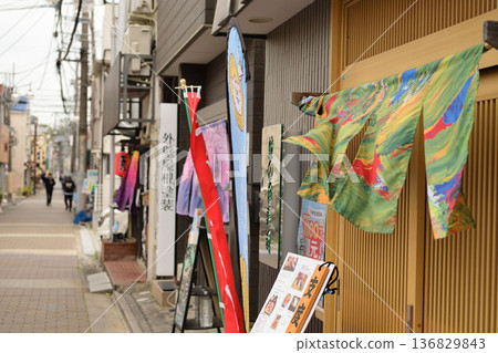 巷子裡商店門前飄動著色彩繽紛的暖簾，構成了一幅熱鬧的商業街景象。 136829843