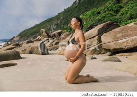 Pregnant smiling woman in swimwear enjoying on beach Pregnant smiling woman in swimwear enjoying on beach 136830152