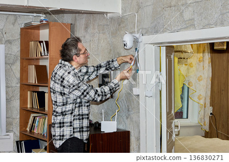 Farmer evaluates performance of new surveillance camera installed inside rural home to monitor domestic pets when they are alone in house. 136830271