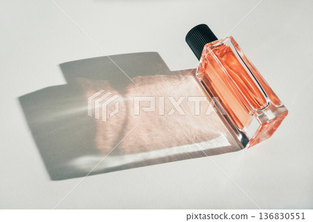 Perfume bottle presenting luxury fragrance with sunlit shadow and reflection 136830551