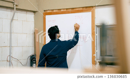 Carpenter drafting woodworking blueprint in workshop 136830685