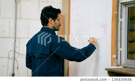 Woodworker drawing carpentry plans on whiteboard 136830686