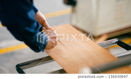 Carpenter sawing wood plank in workshop Carpenter sawing wood plank in workshop 136830697