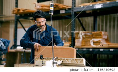 Carpenter cutting wood plank using industrial band saw Carpenter cutting wood plank using industrial band saw 136830698