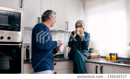 Senior couple enjoying morning coffee and conversation in kitchen Senior couple enjoying morning coffee and conversation in kitchen 136830727