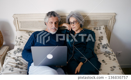 Senior couple relaxing in bed watching laptop 136830757